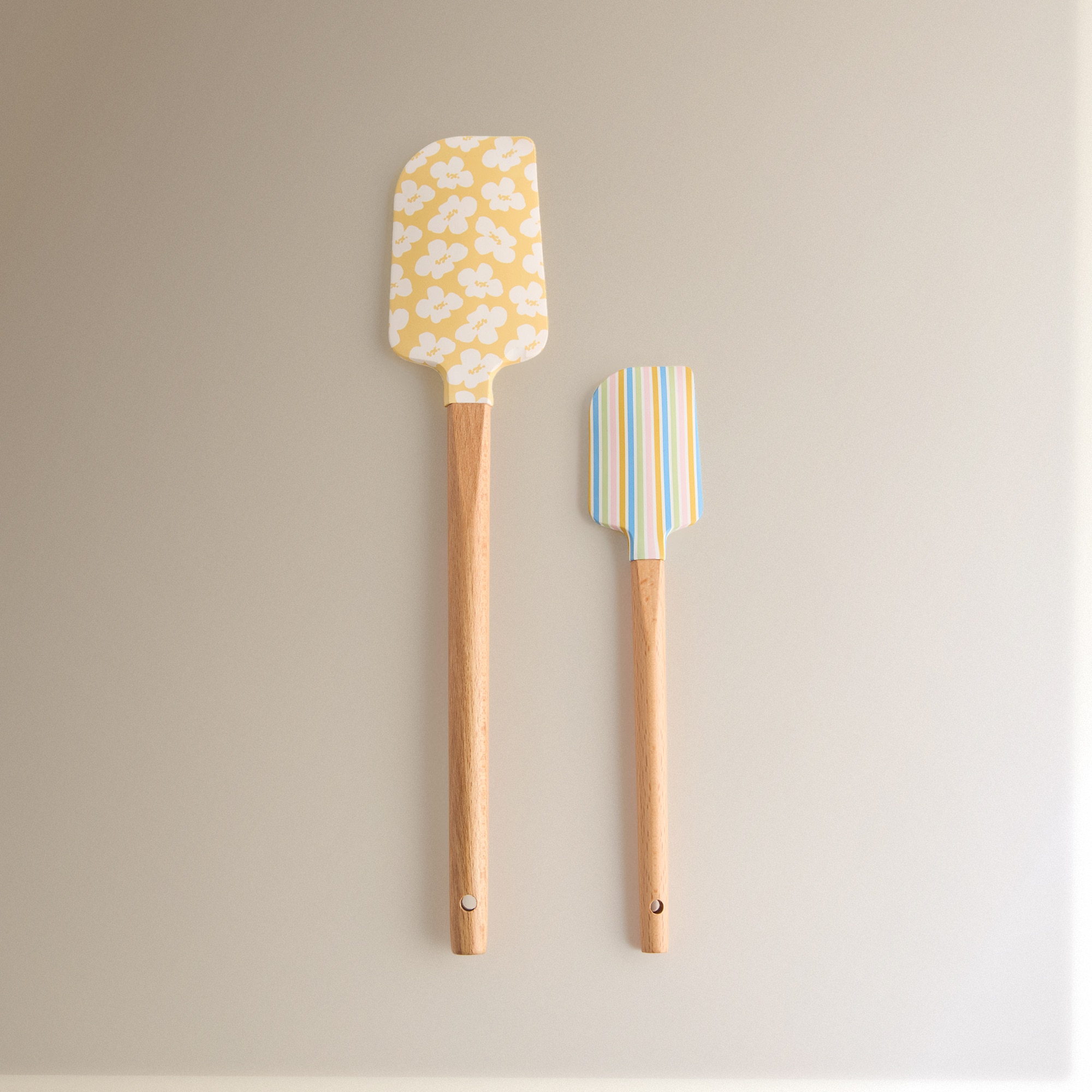 Imagem 0 de Conjunto de duas espátulas de silicone com cabo de madeira, perfeitas para o ajudar na cozinha. São decoradas com desenhos florais e riscas.