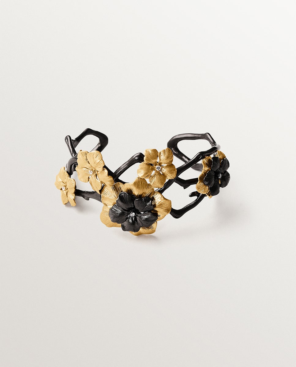Pulsera rígida bicolor bañada en oro amarillo con cristales y motivo de flor
